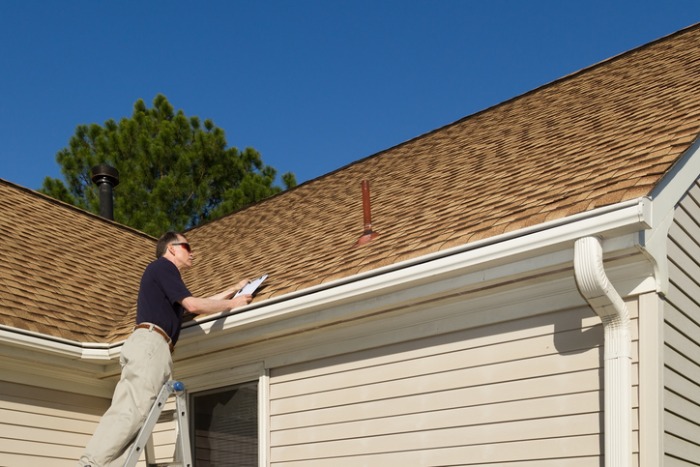 A home inspector examining a residential roof during an inspection.