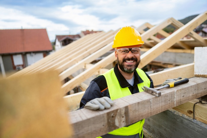 Roofer working on a roof beam at a construction site.