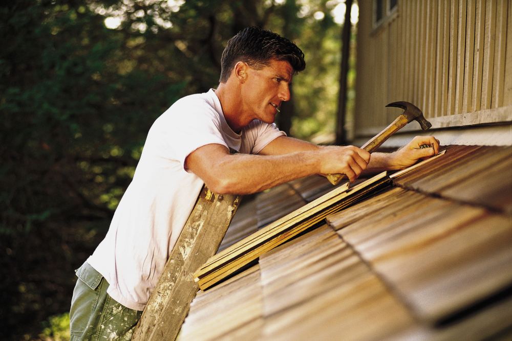 Man repairing cedar shake roof leaks in Portland, OR