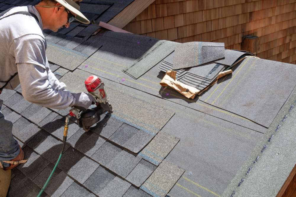 Worker installing composite roofing shingles for durable roof protection